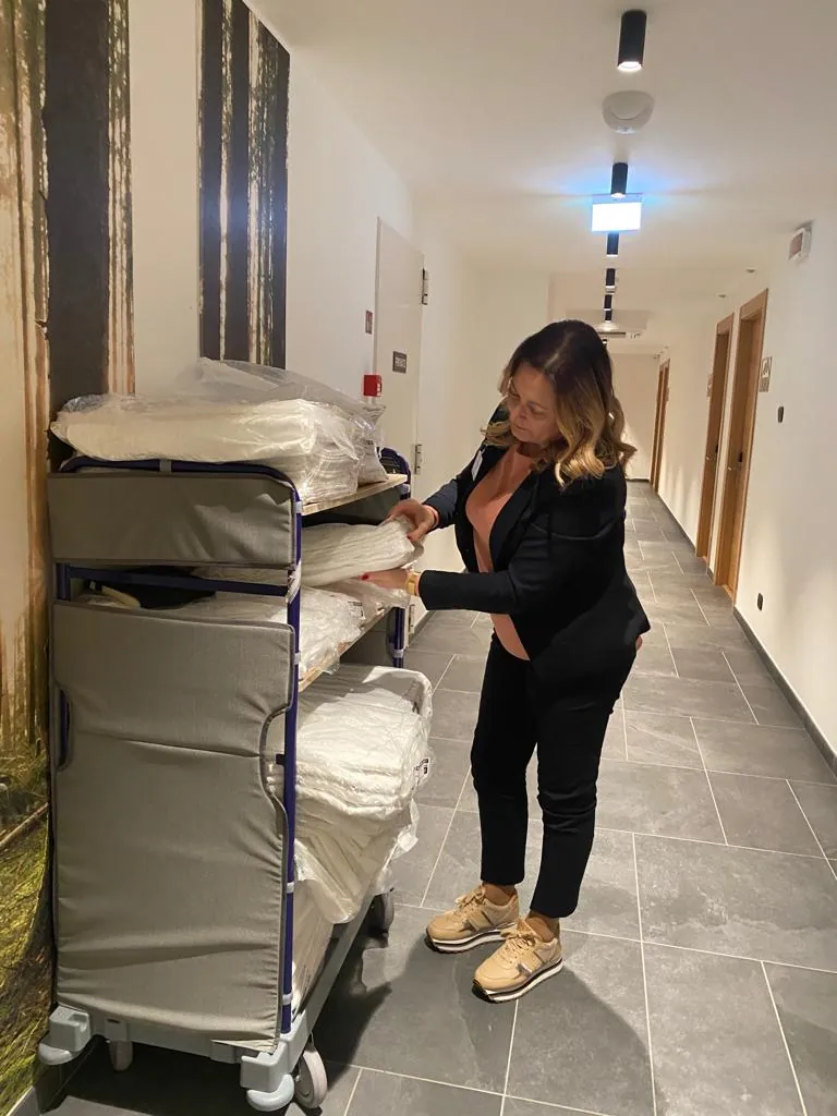 Addetta housekeeping con carrello biancheria nel corridoio di un hotel